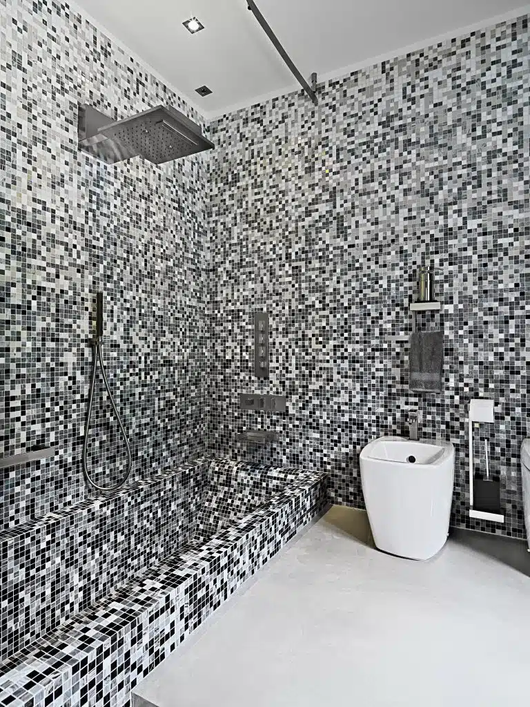 interior view of a mdern bathroom in foreground shower vubicke and sanitayware with mosaic tiles black and white bathroom floor tiles