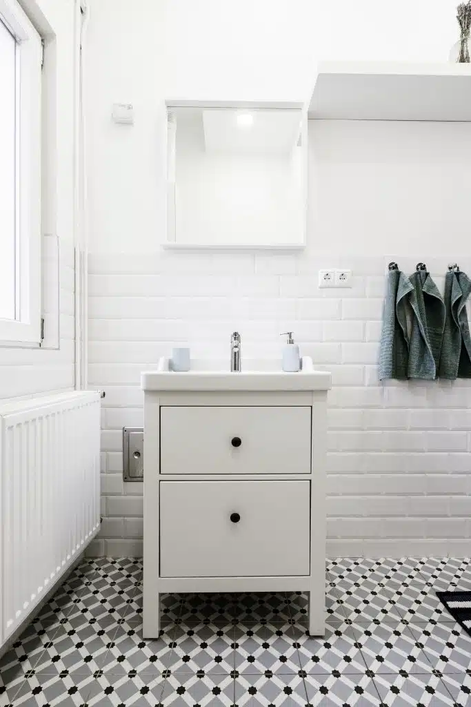 black and white bathroom floor tiles A little white drawer in a white bathroom with hygiene care items on it